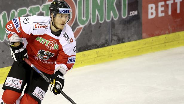 Ein Eishockeyspieler in rot-weißer Uniform mit der österreichischen Flagge auf dem Eis.