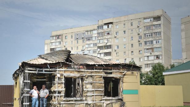 Zwei Männer stehen vor einem durch einen Brand zerstörten Gebäude.