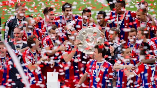Die Fußballmannschaft des FC Bayern München feiert mit der Meisterschale im Konfettiregen.