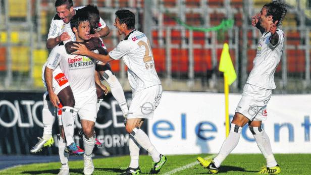 Fußballspieler feiern ein Tor auf dem Spielfeld.