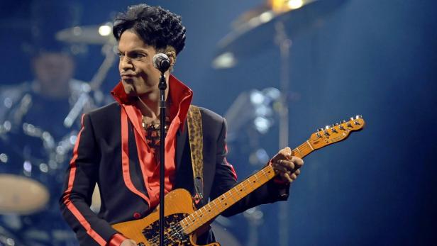 Prince spielt Gitarre während eines Konzerts.