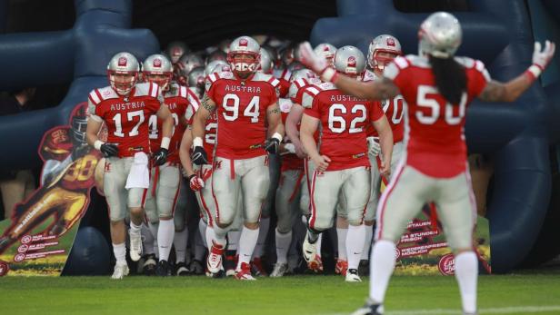 Eine Gruppe American-Football-Spieler in rot-weißen Trikots läuft aus einem Tunnel.