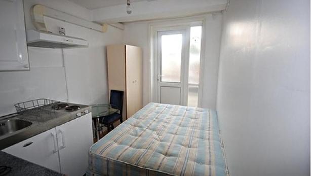 Ein kleines Studio-Apartment mit Küchenzeile und einem Bett.