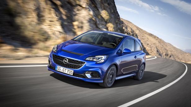 Ein blauer Opel Corsa fährt auf einer kurvenreichen Straße.