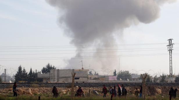 Syrians run for cover as smoke rises over the Syrian town of Ras al-Ain after an air strike, as seen from the Turkish border town of Ceylanpinar, Sanliurfa December 3, 2012. REUTERS/Laszlo Balogh (TURKEY - Tags: POLITICS CONFLICT)