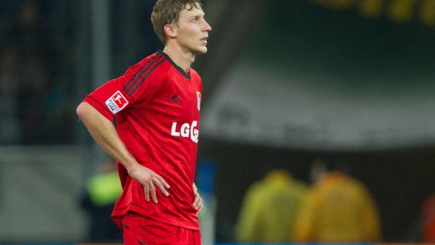 Ein Fußballspieler in roter Spielkleidung steht mit den Händen in den Hüften.