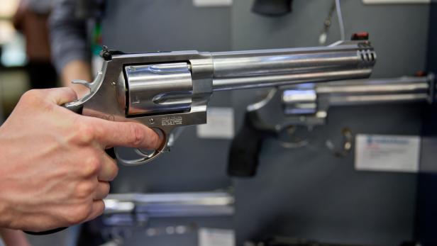 Eine Hand hält einen silbernen Revolver.