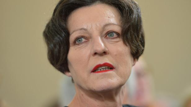 Porträt einer Frau mit roten Lippen und kurzen, dunklen Haaren.