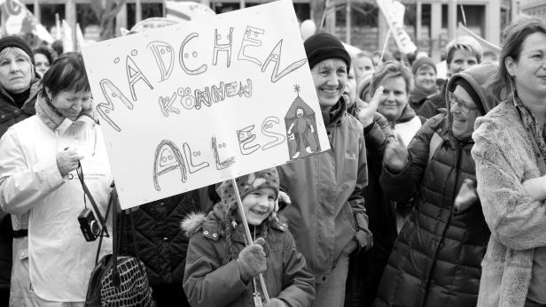 Eine junge Demonstrantin hält ein Schild mit der Aufschrift „Mädchen können alles“.