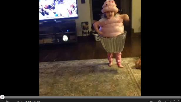 Ein kleines Mädchen tanzt verkleidet als rosa Cupcake.