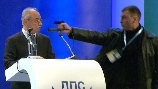 epa03544261 A still grab from a broadcast by Bulgarian television channel BTV handed out by BTV on 19 January 2013 shows an unidentified man (R) pointing a gun at Ahmet Dogan (C), leader of the MRF party of the Turkish minority in Bulgaria, during a party conference in Sofia, Bulgaria, 19 January 2013. The leader of Bulgaria&#039;s opposition Movement for Rights and Freedoms escaped an apparent assassination attempt 19 January while addressing a party congress in Sofia, local media reported. The attacker pointed a gun at Dogan, but was prevented from firing, according to the reports. While security wrestled with the attacker, Dogan was tackled to the ground by his bodyguards. The oppositional Movement for Rights and Freedoms (MRF) has deputies in the National Assembly in Sofia and in the EU parliament. EPA/BTV / HANDOUT RECROPPED VERSION OF BTV01 * MANDATORY CREDIT: BTV HANDOUT EDITORIAL USE ONLY/NO SALES