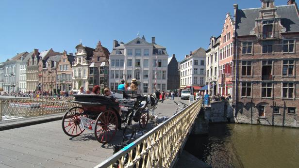 Eine Pferdekutsche fährt über eine Brücke in einer historischen Stadt.