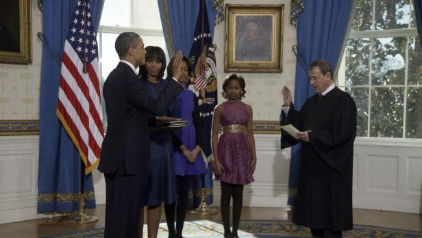 epa03546608 President Barack Obama is officially sworn-in by Chief Justice John Roberts in the Blue Room of the White House during the 57th Presidential Inauguration in Washington, Sunday, Jan. 20, 2013. Next to Obama are (L-R) First Lady Michelle Obama, holding the family bible, and daughters Malia and Sasha. EPA/Charles Dharapak