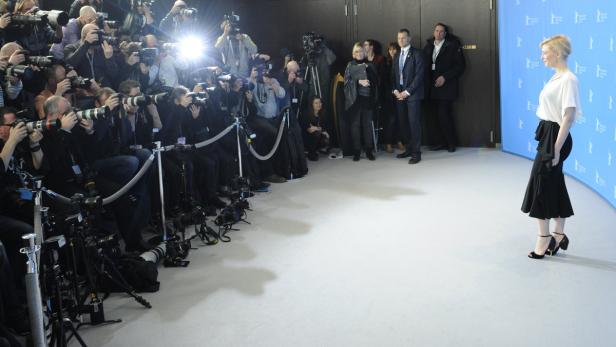 Cate Blanchett posiert vor einer Wand, während sie von einer Gruppe Fotografen fotografiert wird.