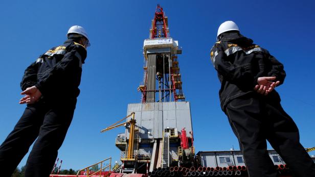 Arbeiter vor einem Ölbohrturm in Sibirien