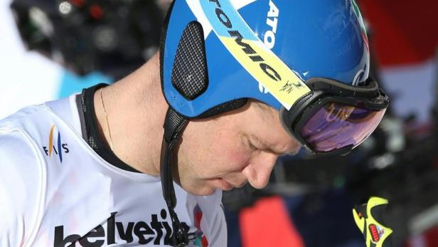 Ein Skirennläufer mit blauem Helm und Skibrille blickt nach unten.