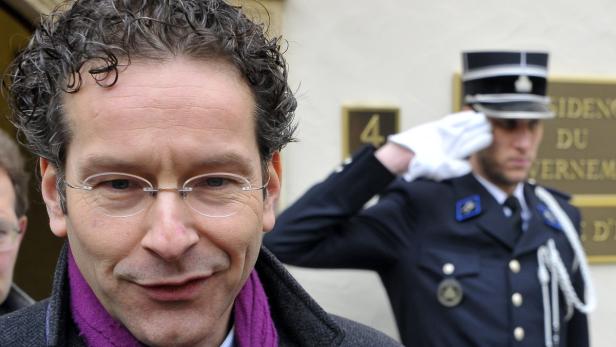 Jeroen Dijsselbloem vor einem Wachmann in Uniform.