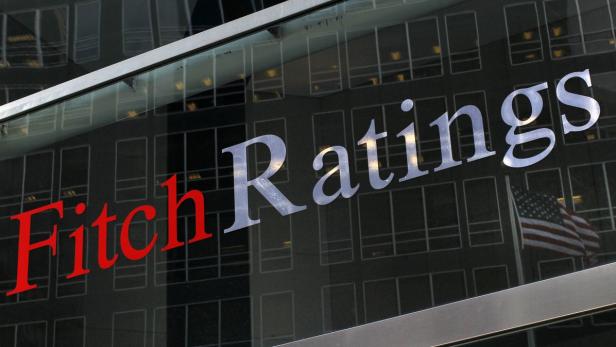 Das Logo von Fitch Ratings an einem Gebäude mit einer amerikanischen Flagge im Hintergrund.
