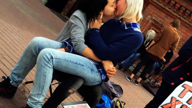 Zwei Frauen sitzen auf der Straße und küssen sich.