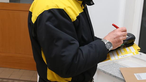 Ein Postbote in Arbeitskleidung notiert etwas auf einem gelben Formular.
