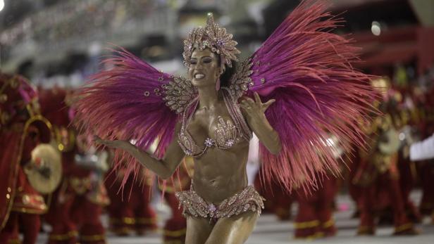 Eine Tänzerin mit Federn und Paillettenkostüm tritt bei einem Karneval auf.