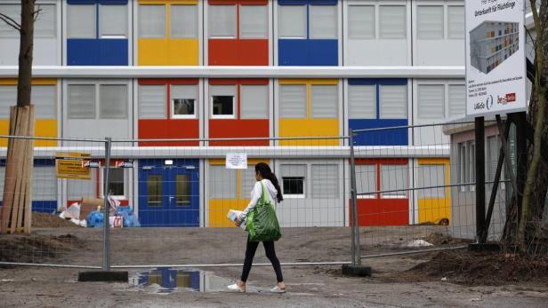 Eine Frau geht vor einem mehrfarbigen Gebäude entlang, das als Unterkunft für Flüchtlinge dient.