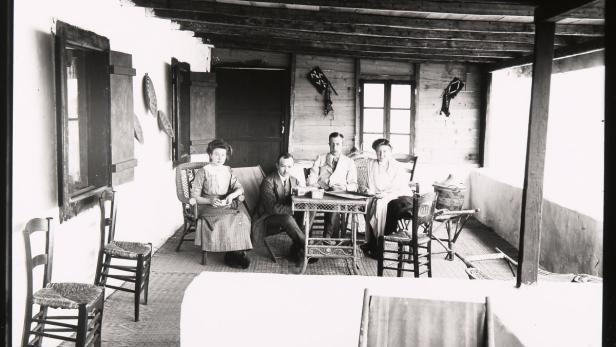 Eine Gruppe von vier Personen sitzt an einem Tisch auf einer Veranda.
