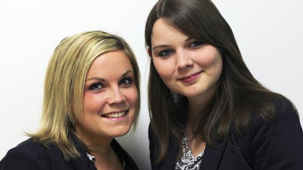Zwei lächelnde Frauen stehen nebeneinander vor einem weißen Hintergrund.