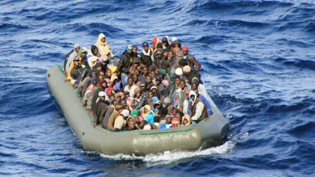 Ein überfülltes Schlauchboot treibt auf dem offenen Meer.