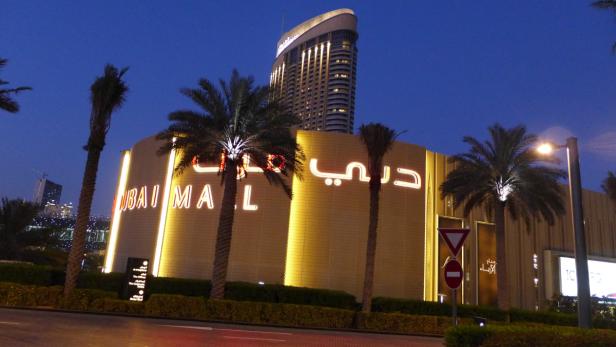 Das Dubai Mall Gebäude mit Palmen bei Nacht.