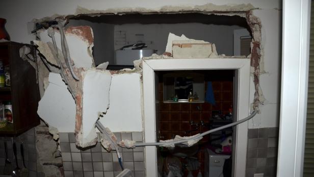Eine zerstörte Wand zwischen Küche und Badezimmer mit freiliegenden Rohren.