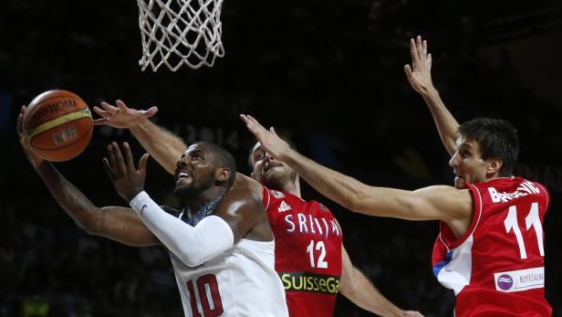Ein Basketballspieler der USA versucht, den Ball am serbischen Team vorbei in den Korb zu werfen.