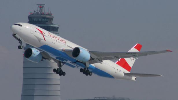 Ein Flugzeug der Austrian Airlines startet vor einem Tower.
