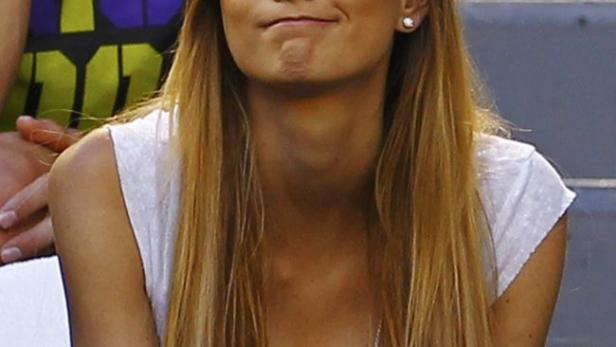 Eine junge Frau mit langen blonden Haaren sitzt auf einer Tribüne.