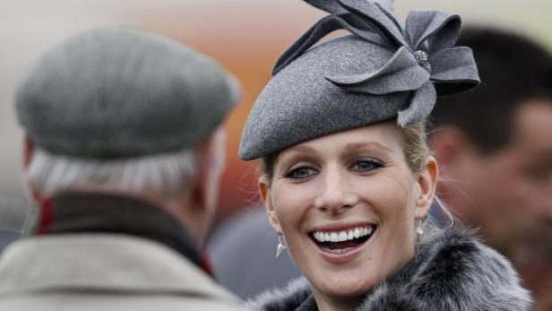 Zara Tindall mit einem grauen Hut und einem Pelzkragen lächelt.