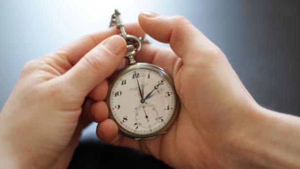 Eine Person hält eine antike Taschenuhr in ihren Händen.