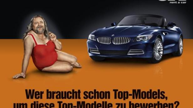 Ein Mann im Badeanzug posiert neben einem blauen BMW Z4 Roadster.