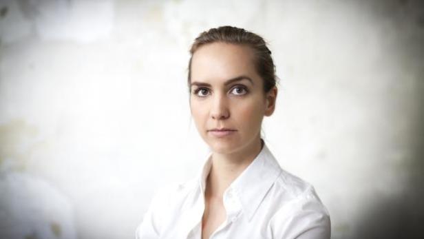 Eine Frau mit weißem Hemd vor einem hellen Hintergrund.