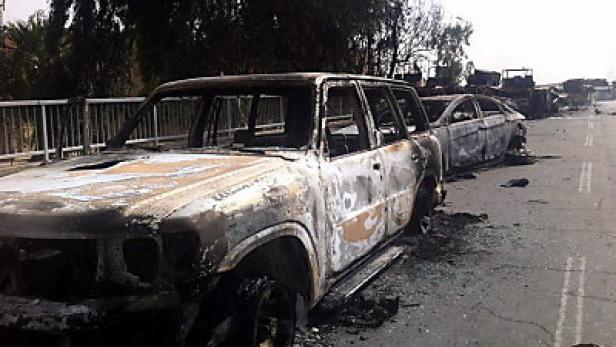 Ausgebrannte Autos stehen auf einer Straße.