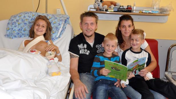 Eine Familie besucht ein Kind mit Armbruch im Krankenhaus.