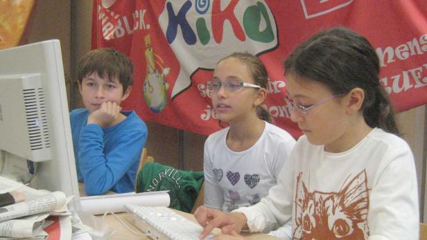 Drei Kinder sitzen vor einem Computer und arbeiten an einem Projekt.