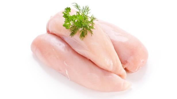 Drei rohe Hähnchenbrustfilets, garniert mit Dill, liegen auf einem weißen Untergrund.