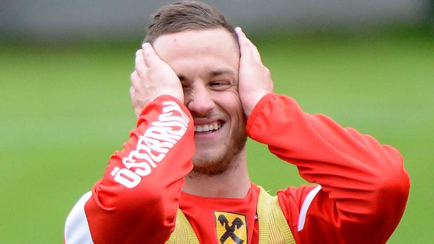 Ein lachender Fußballspieler hält sich die Ohren zu.