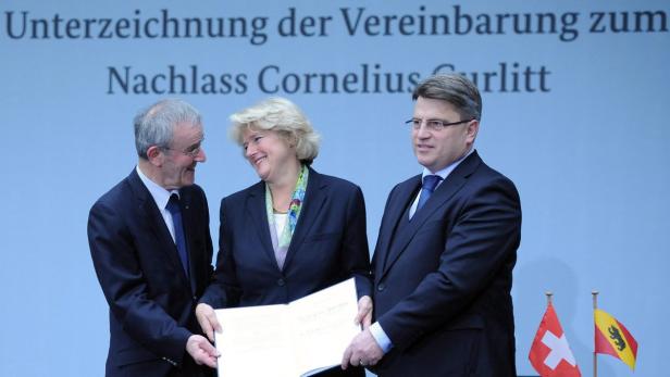 Drei Personen unterzeichnen eine Vereinbarung zum Nachlass Cornelius Gurlitt.