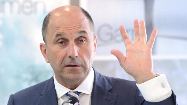 Ein Mann im Anzug hebt seine Hand.