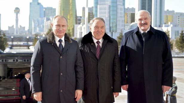 Wladimir Putin, Nursultan Nasarbajew und Alexander Lukaschenko posieren vor einer Skyline.