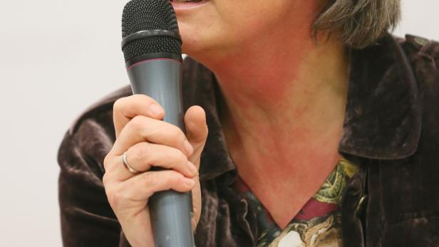 Eine Frau mit grauem Haar spricht in ein Mikrofon.