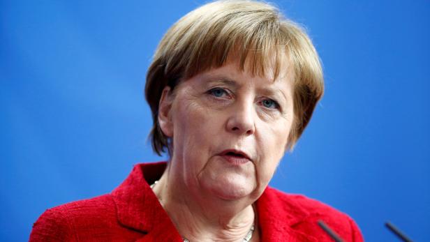 Angela Merkel bei einer Pressekonferenz vor blauem Hintergrund.