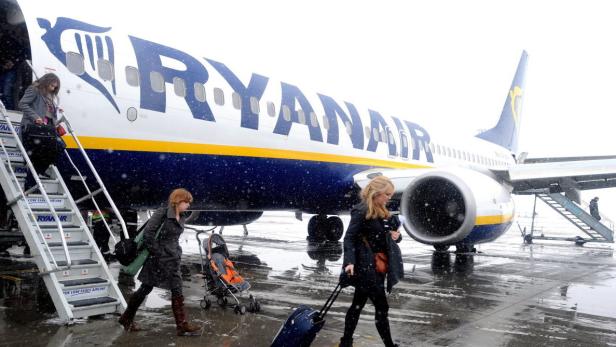 Passagiere verlassen ein Flugzeug von Ryanair auf einem verschneiten Flugfeld.