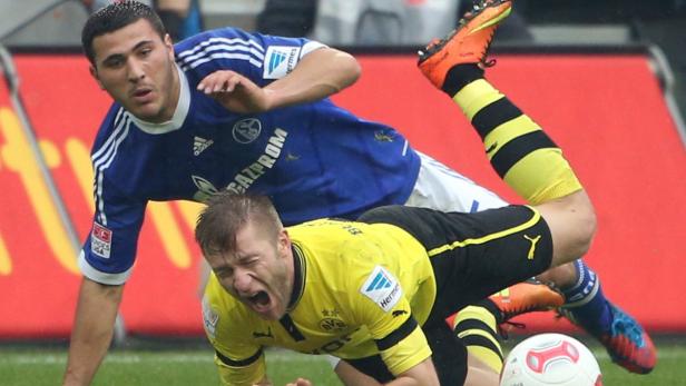 Zwei Fußballspieler kämpfen um den Ball auf dem Spielfeld.